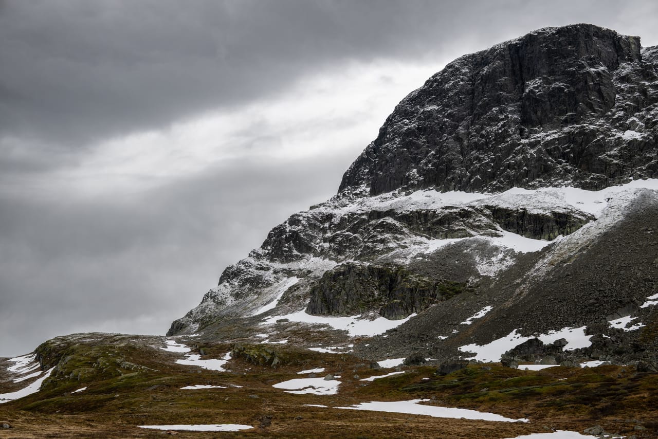 Bratt, snøstripet fjellparti på Valdresflye under et tungt skydekke.