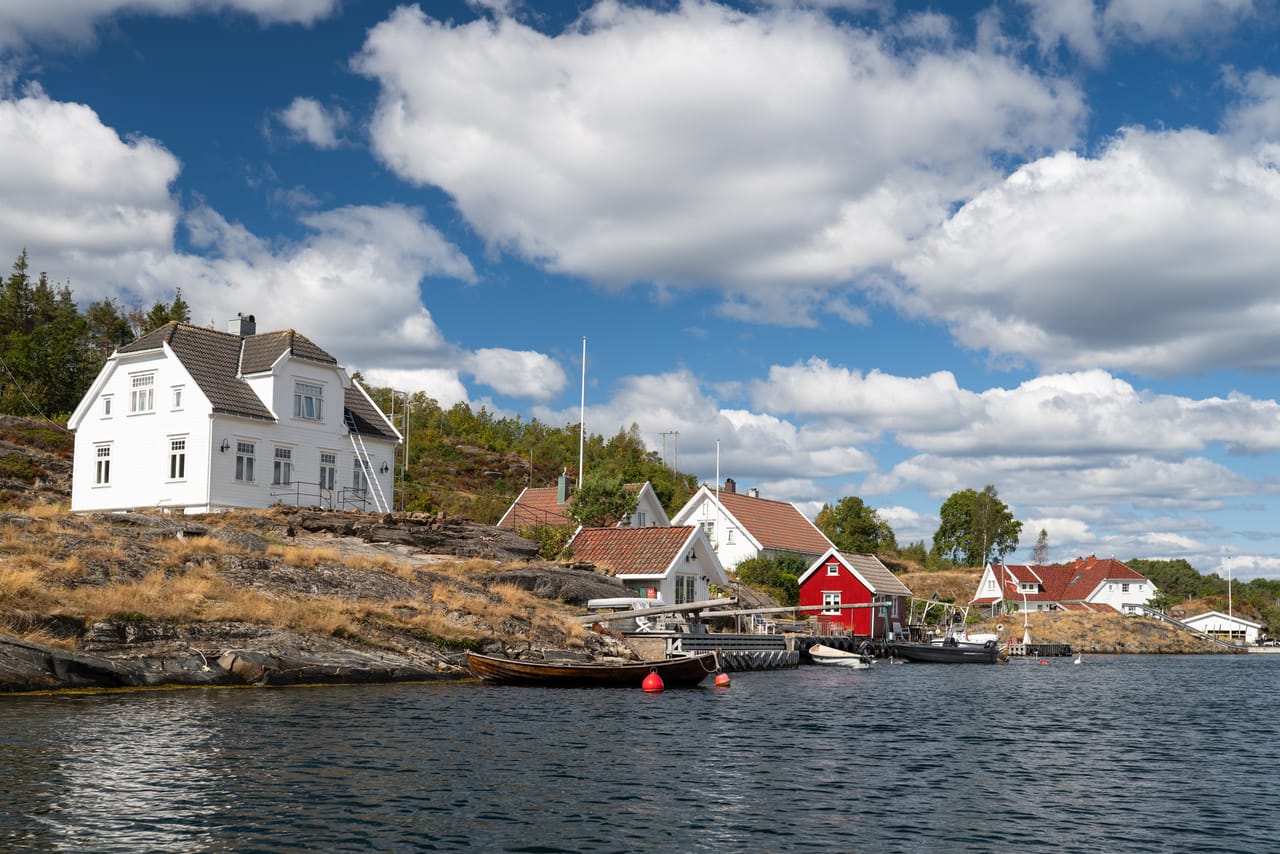 Hyttebebyggelsen langs Skippergata ved Randøya, med båter fortøyd ved en liten brygge.