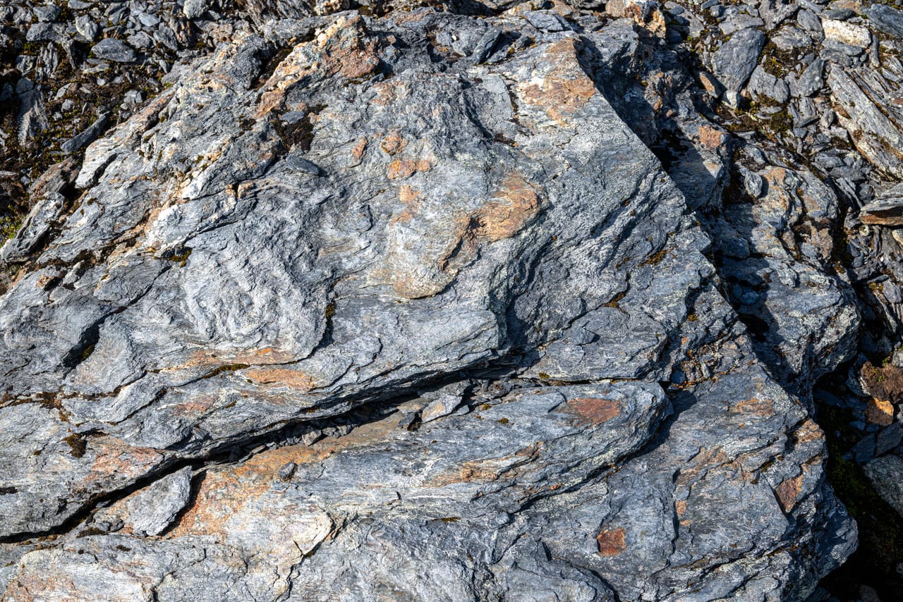 Nærbilde av skifer med lyse årer av mineraler i berget.